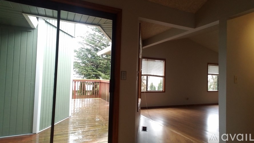 A room with wooden floors and a balcony with a view of trees.