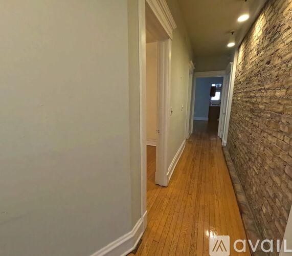 A long hallway with a brick wall on the side and wooden floors.