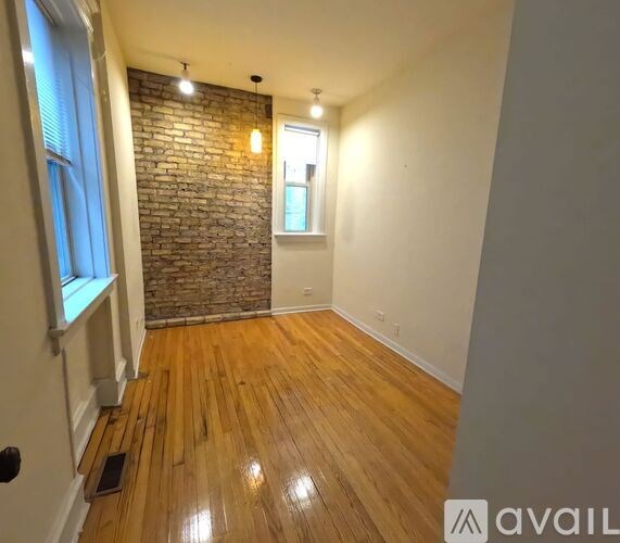 A room with wooden floors and a brick wall.