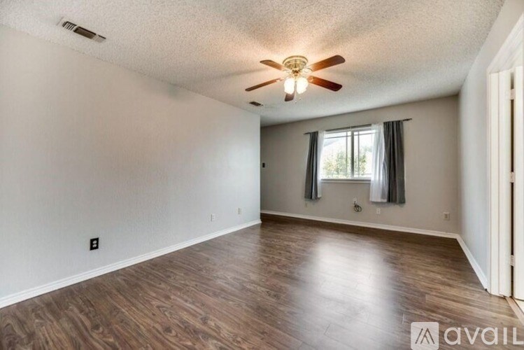 A room with a ceiling fan and wooden flooring.