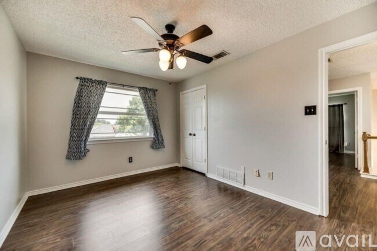 A room with a ceiling fan and wooden flooring.