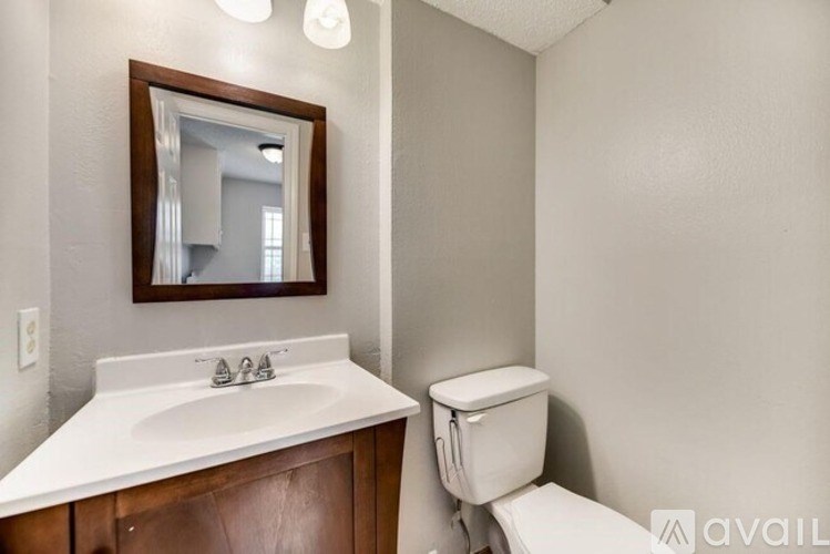 A bathroom with a toilet, sink, and mirror.