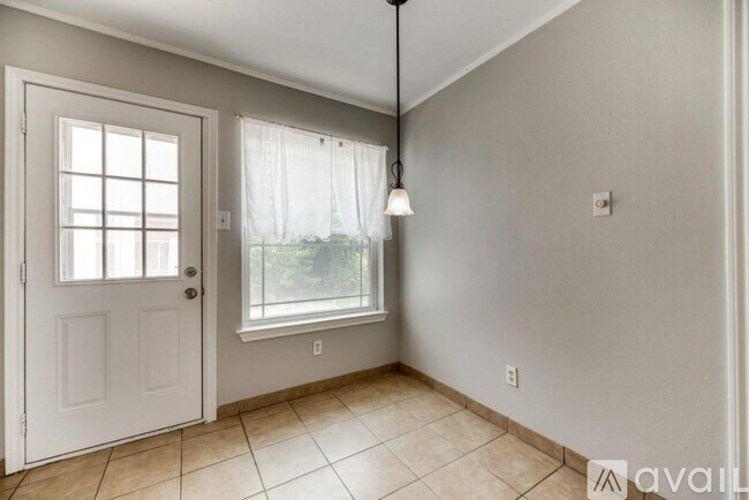 A room with a white door, a window with white curtains, and a hanging light fixture.