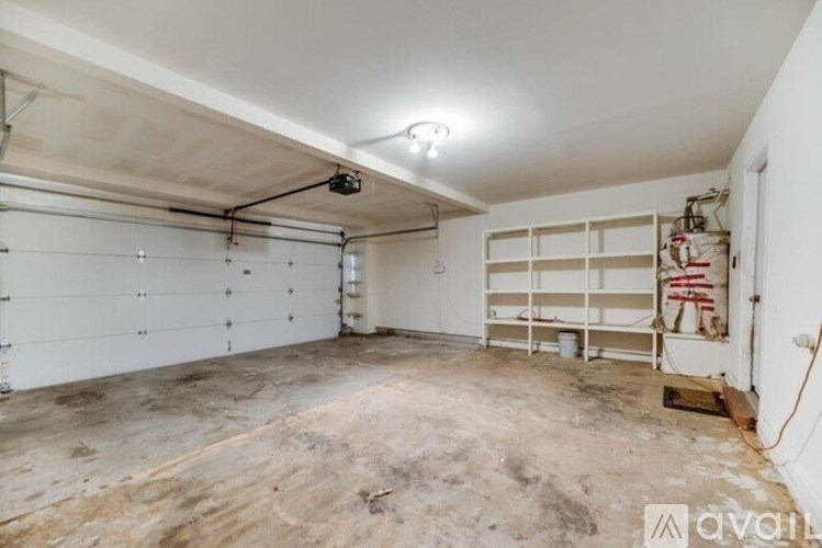 A spacious garage with a white ceiling and walls, and a concrete floor.
