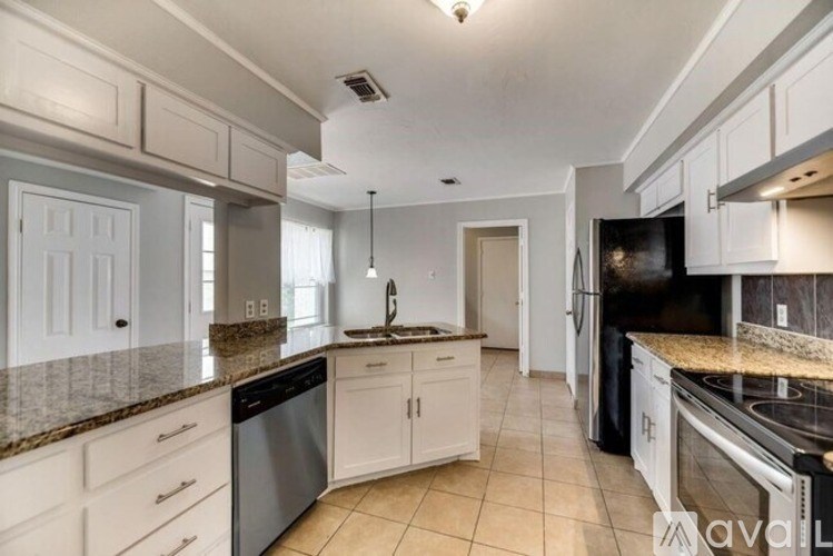 A kitchen with white cabinets and granite countertops.