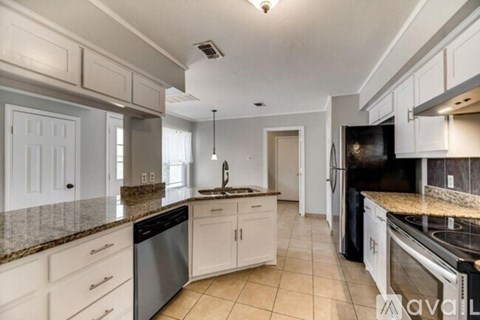 A kitchen with white cabinets and granite countertops.