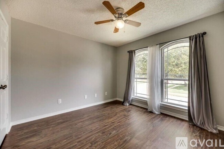 A room with a ceiling fan and a window with curtains.