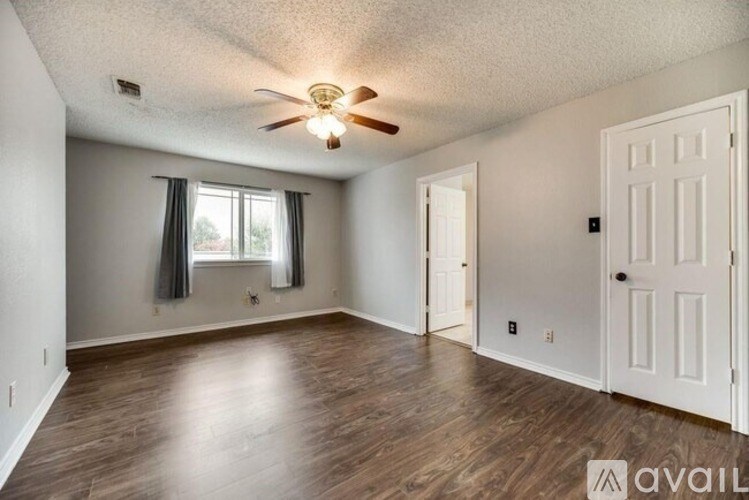 A room with a ceiling fan and wooden flooring.