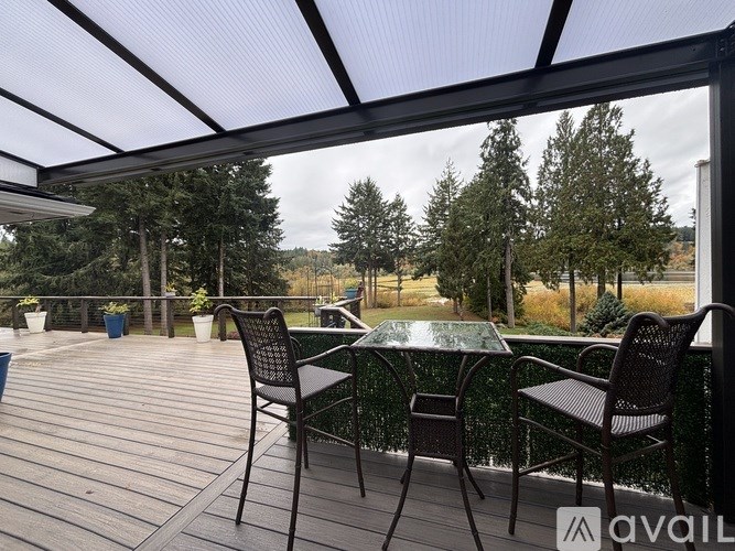A patio with a glass table and chairs overlooking a wooded area.