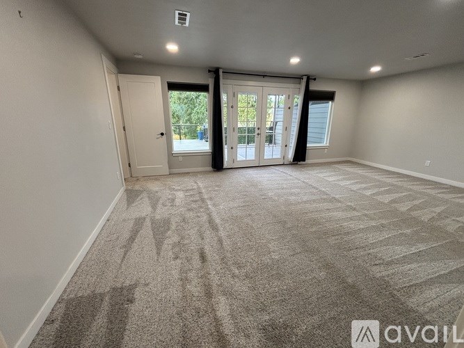 A spacious room with a carpeted floor and sliding glass doors leading to a balcony.