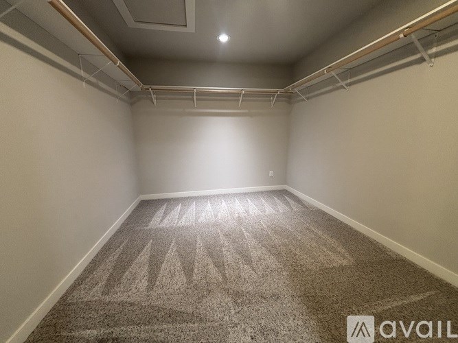 A carpeted room with a light on the ceiling and a wall on the left side.