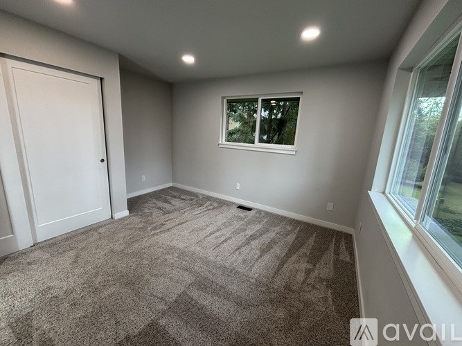 A room with a carpeted floor, a window, and a door.
