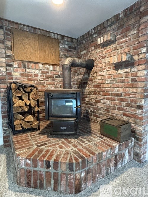 A black TV sits on a brick stand with a wood pile to its left.