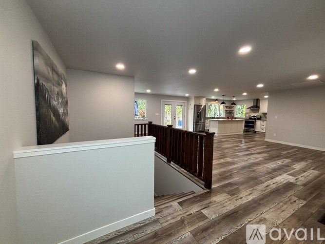 A spacious room with wooden flooring and a staircase leading to the upper level.