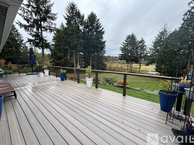 A wooden deck with a table and chairs overlooking a grassy area.