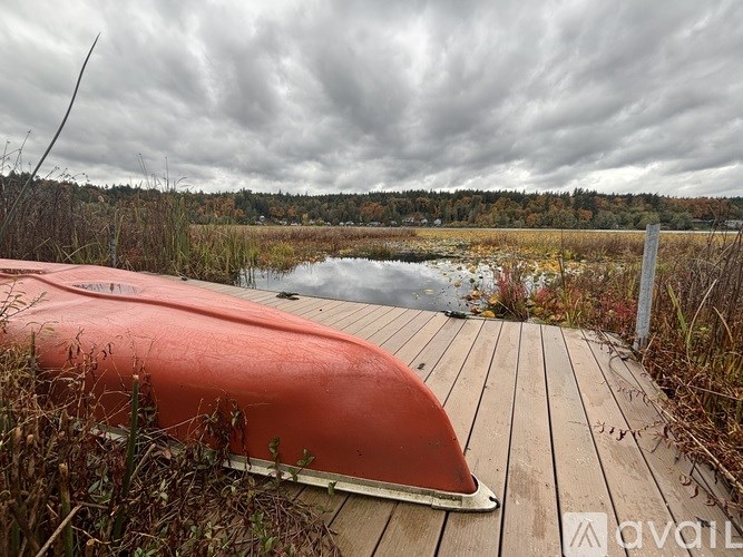 A red kayak is on a wooden dock by a body of water.