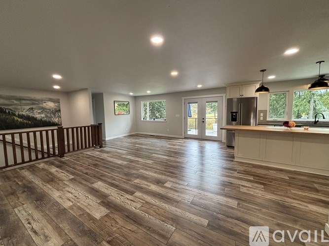 A spacious room with wooden flooring and a large window.