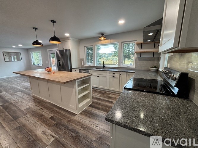 A kitchen with a wooden island and granite countertops.