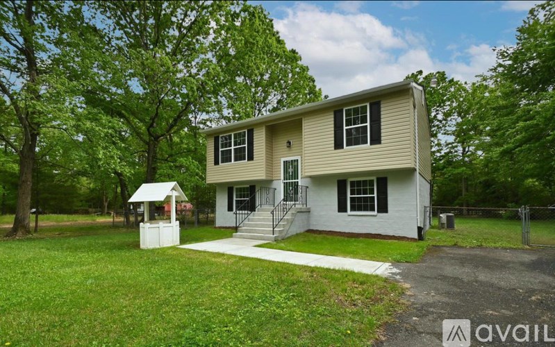 A house with a white porch and a white gazebo in the front yard.