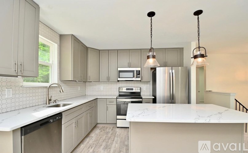 A modern kitchen with a white marble countertop and stainless steel appliances.