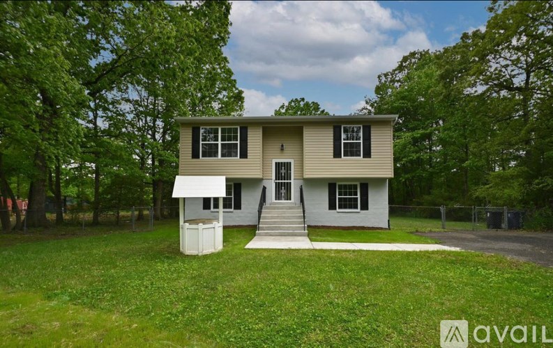 A two-story house with a front porch is surrounded by greenery.