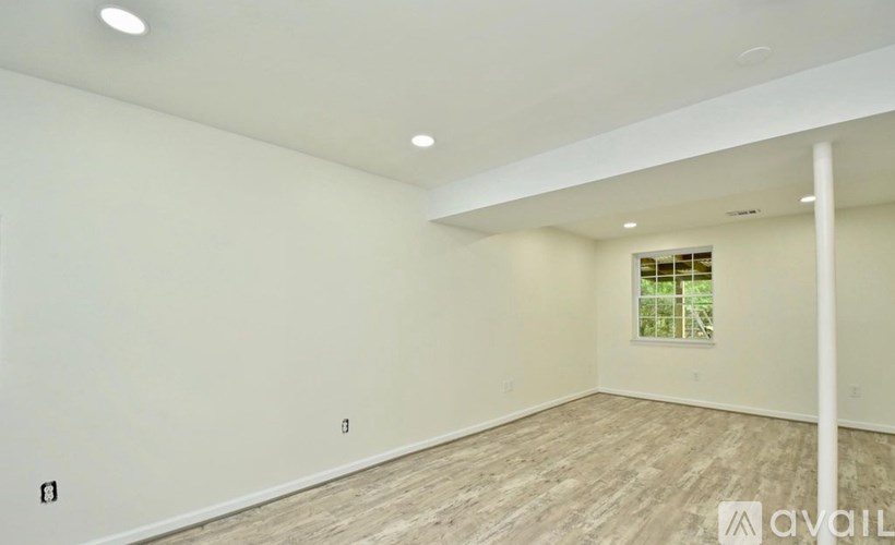 A spacious room with wooden flooring and white walls.