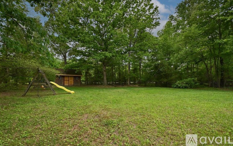A playground with a yellow slide is surrounded by trees.