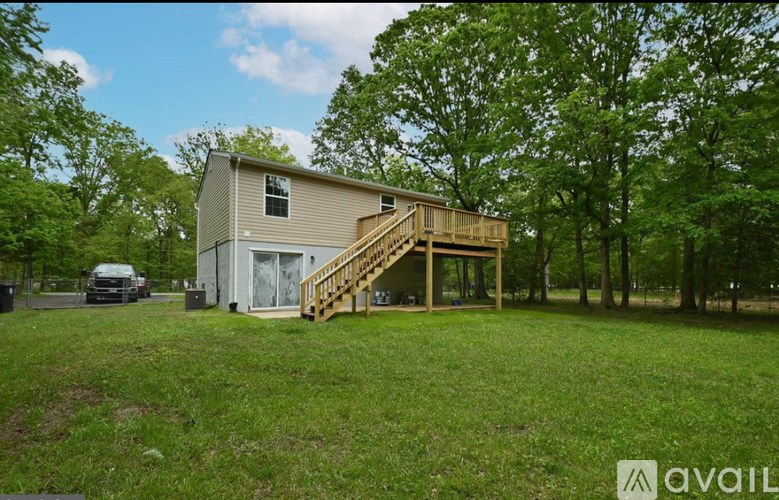 A house with a deck and a car parked in front.