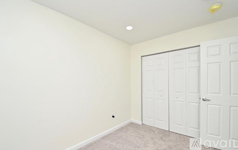 A room with a white door and a carpeted floor.