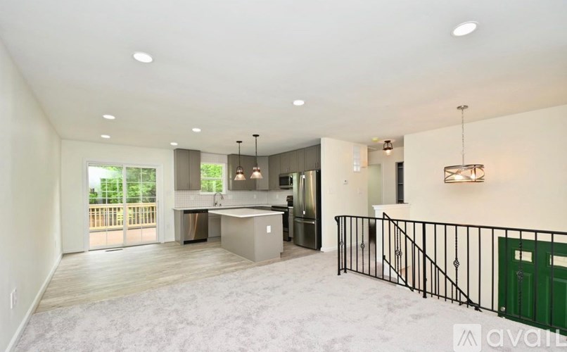 A spacious living room with a kitchen area in the background.