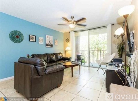 A living room with a brown leather couch and a ceiling fan.