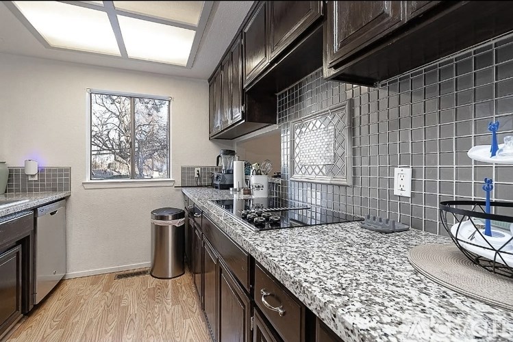 A kitchen with a marble countertop and dark wood cabinets.