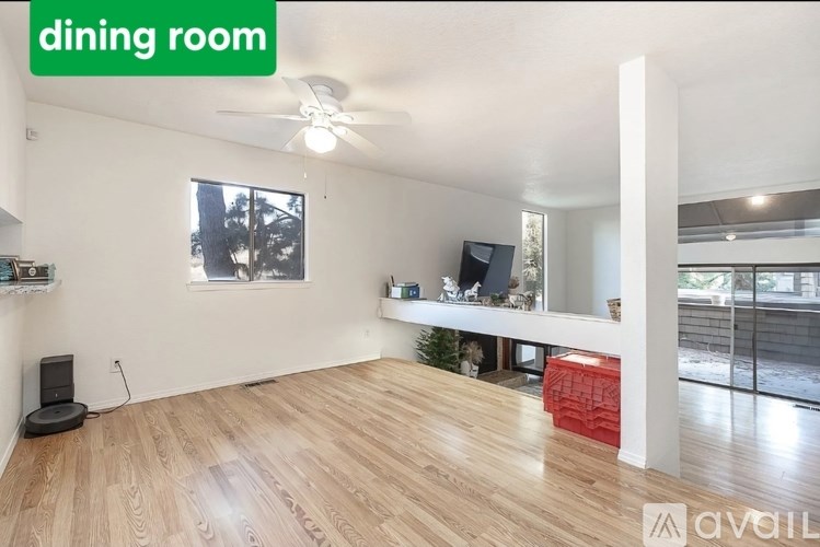 A dining room with a fan, wooden flooring, and a window.