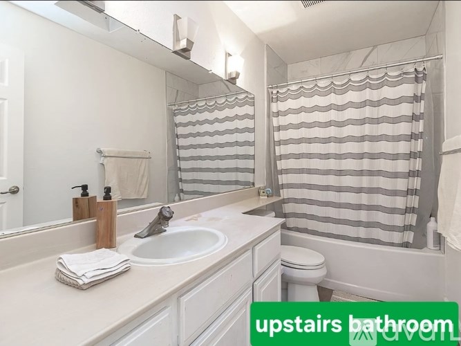 A bathroom with a sink, toilet, and shower curtain.