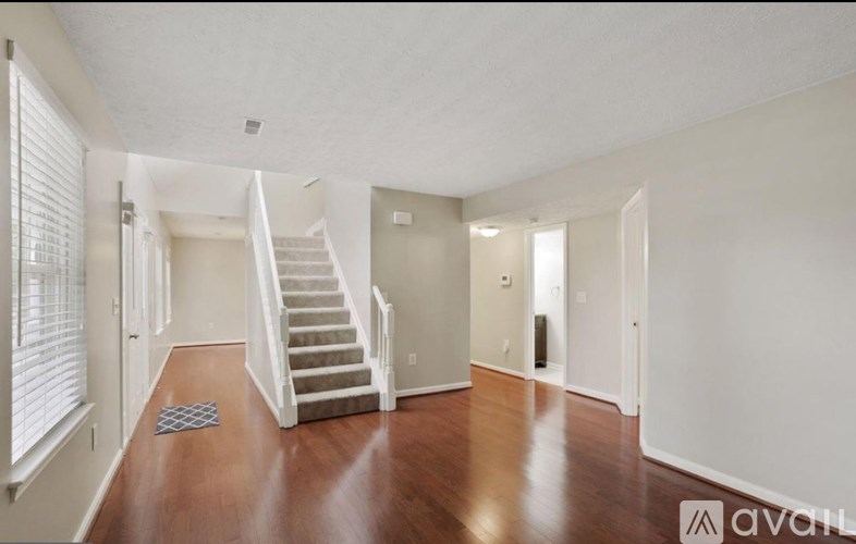 A spacious room with wooden floors and a staircase leading to another level.