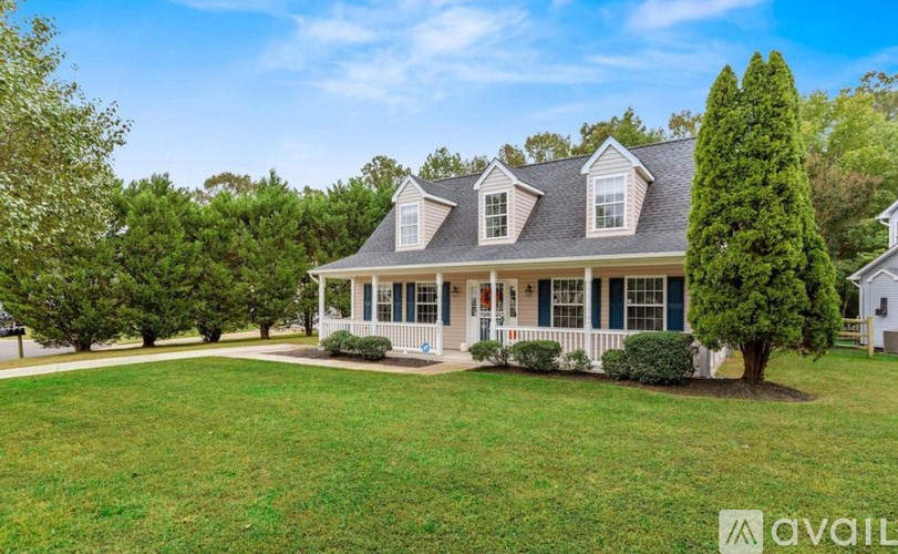A house with a large front yard and a tree in the front.