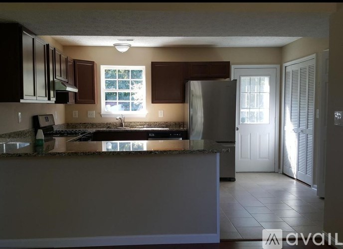 A kitchen with brown cabinets and a stainless steel refrigerator.