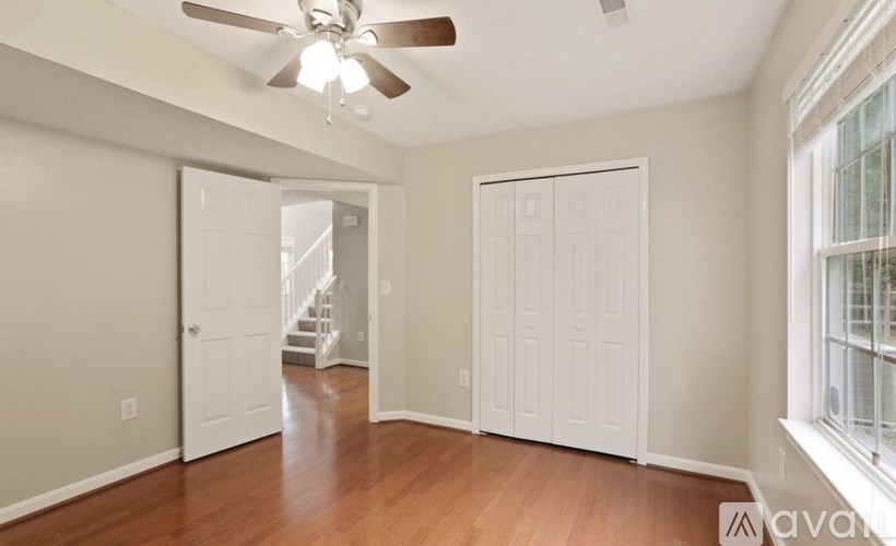 A room with a ceiling fan and wooden floors.