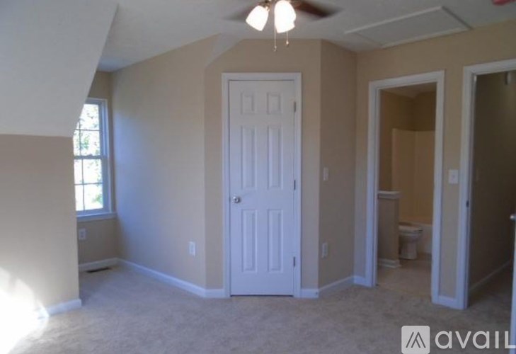 A room with a white door and a window on the left side.