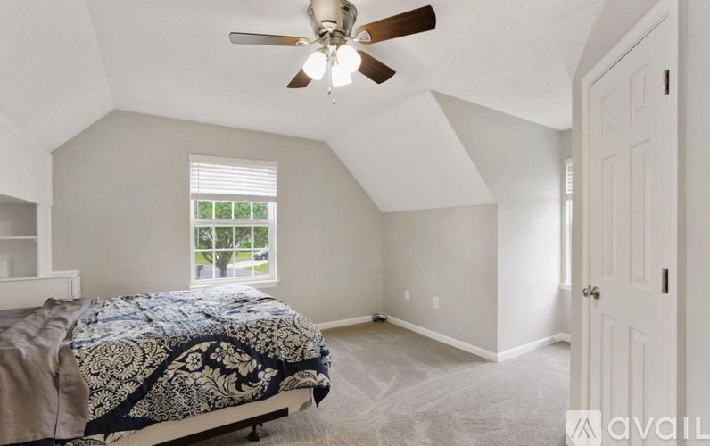 A bedroom with a bed, ceiling fan, and a window.