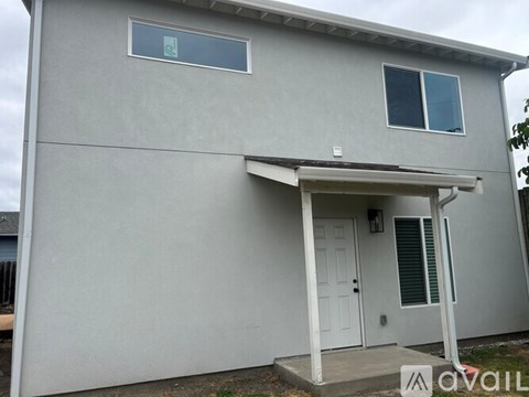 A grey house with a white door and a small window above it.