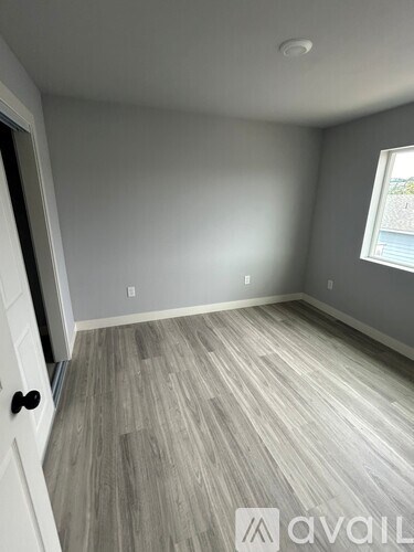 A room with grey flooring and a window letting in natural light.