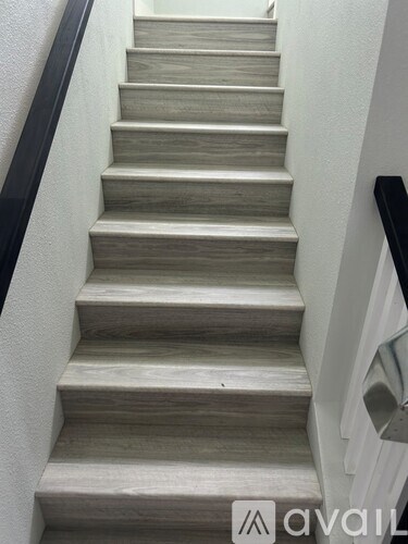 A set of stairs with a black railing and wooden steps.