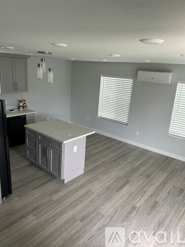 A room with a white fridge and wooden flooring.