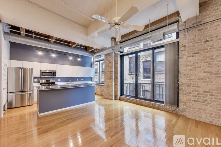 A spacious kitchen and living room with wooden floors and a brick wall.