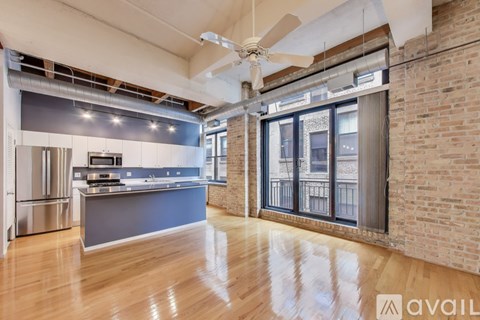 A spacious kitchen and living room with wooden floors and a brick wall.
