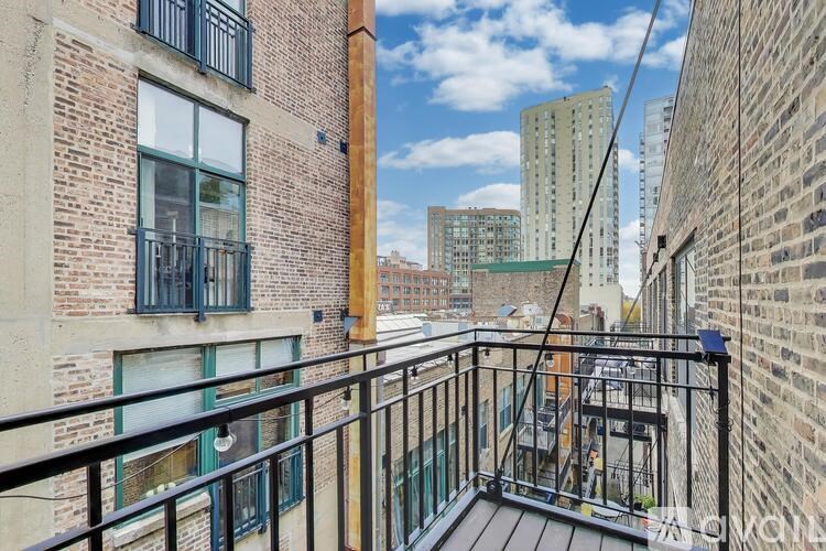 A balcony with a black railing overlooks a cityscape.