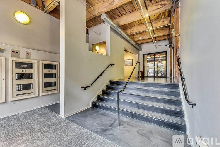 A staircase with a black handrail and a grey carpeted floor.
