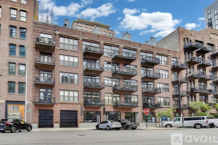 A street view of a multi-story building with cars parked in front.