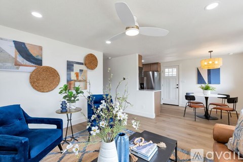 A living room with a blue chair and a white ceiling fan.